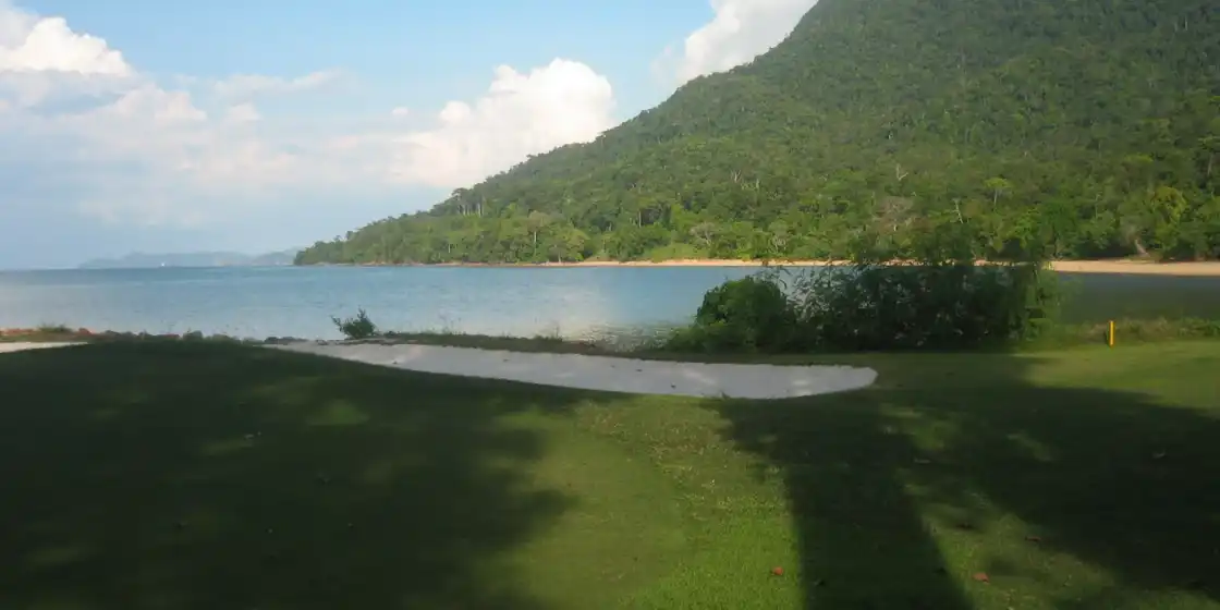 Greenside bunker by the sea below forested hills at The Els Club Teluk Datai, Langkawi