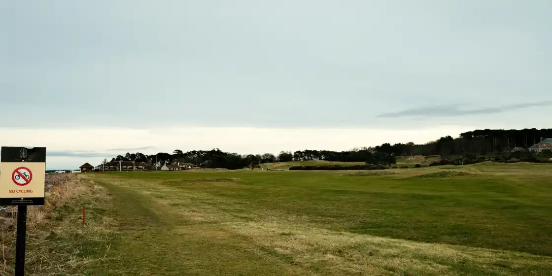 Links fairways at Nairn Golf Club running toward the clubhouse beside the Moray Firth