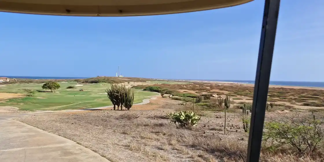 Fairways among cactus and dry scrub with the sea beyond at Tierra del Sol Golf Course, Aruba